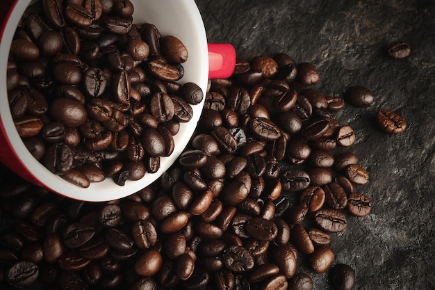 Kaffeebohnen in einer Tasse auf schwarzem Steinhintergrund