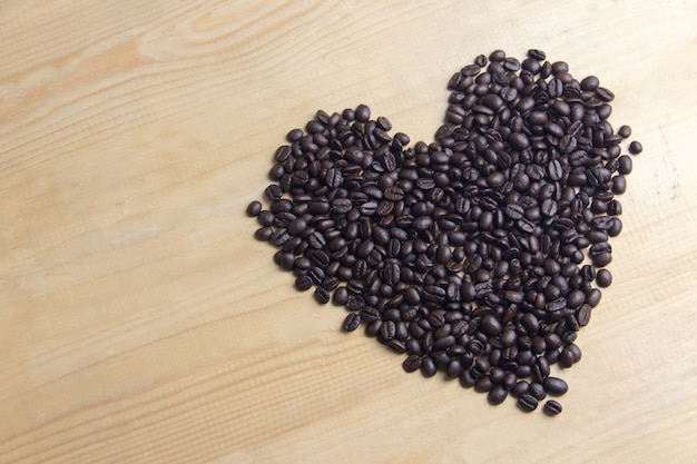 Foto kaffeebohnen in form des herzens auf hölzernem des brauns