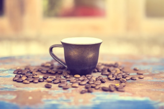 Kaffeebohnen mit einer Tasse auf einem alten Tisch