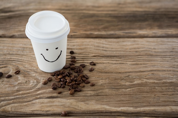 Kaffeebohnen und Einwegkaffeetasse mit Smiley