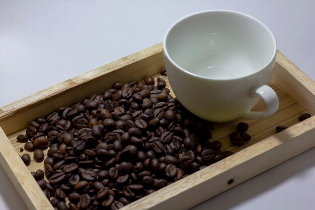 Kaffeebohnen und Glas sind auf Holz weiß.