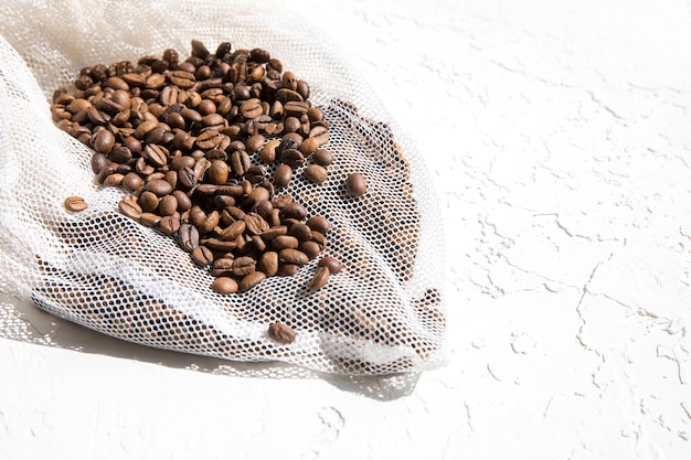 Kaffeebohnen und lose weiße Netztasche.