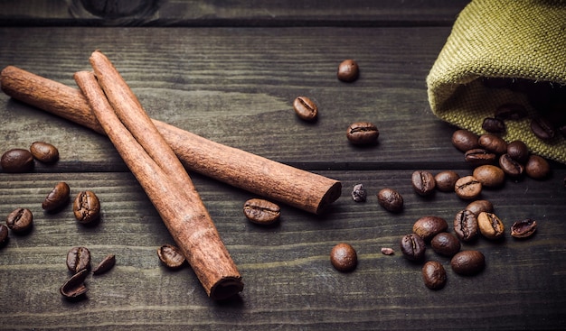 Kaffeebohnen, Zimt, Tasche auf einem dunklen hölzernen Hintergrund.