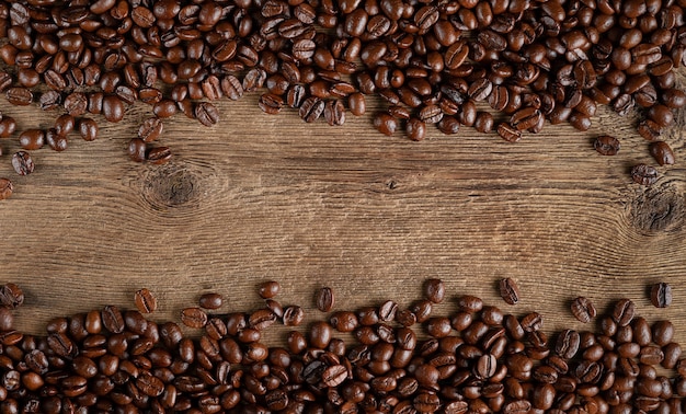 Kaffeebohnenrahmen auf rustikalem hölzernem Hintergrund. Kopieren Sie Platz direkt darüber.