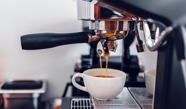 Kaffeeextraktion aus der Kaffeemaschine mit einem Siebträger, der Kaffee in eine Espressotasse gießt