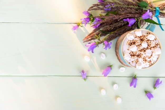 Kaffeegetränk mit Marshmallows und einem Strauß zarter Blumen