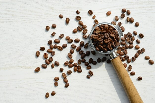 Kaffeehorn mit Kaffeebohnen auf einem weißen Holztisch Draufsicht Kaffeezubereitung