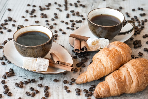 Kaffeekörner auf Holztisch mit Süßigkeiten und Croissant