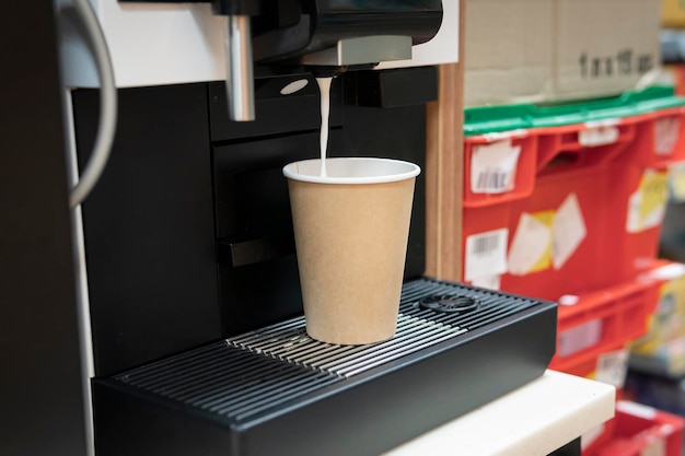 Kaffeemaschine gießt heißen Kaffee in eine Papptasse und bereitet Espresso zu