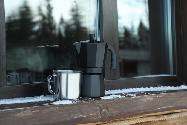 Kaffeemaschine und Metallbecher im Freien auf der Fensterbank