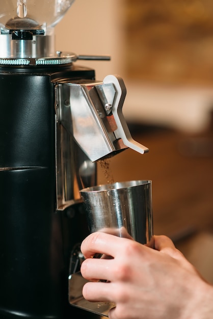 Kaffeemühle füllt Kaffee in eine Tasse.