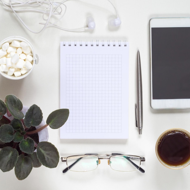 Kaffeepause am Arbeitsplatz. Flache Lage von Telefon, Notizblock, Blumentopf und Kaffee mit Kopierraum