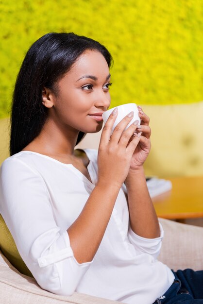 Kaffeepause genießen. Seitenansicht einer nachdenklichen jungen Afrikanerin, die Kaffee trinkt und wegschaut