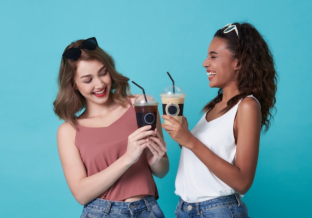 Kaffeepause, glückliche Frauen, die Eiskaffee auf Blau halten