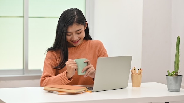 Kaffeepause, junge kreative Frau, die Kaffeetasse und das Lächeln hält.