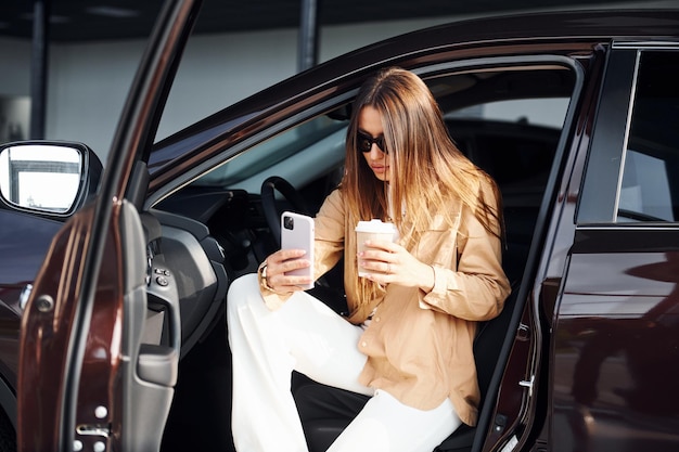 Kaffeepause Modische schöne junge Frau und ihr modernes Automobil