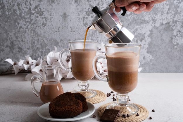 Kaffeeschaum wird in einen Becher mit Milch gegossen Latte machen