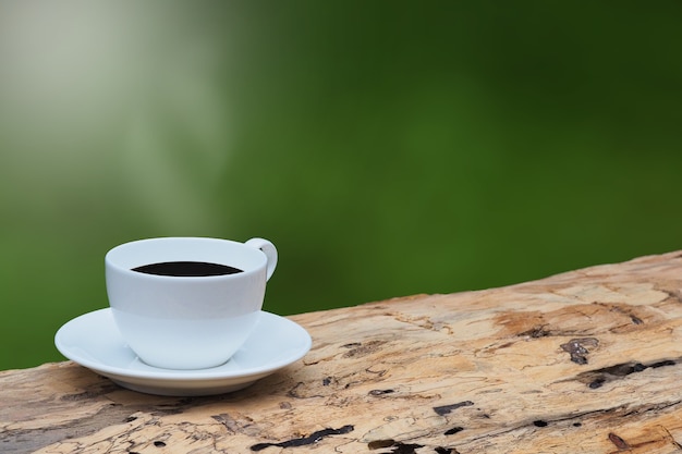 Kaffeetasse auf braunem Holz morgens und grünem Hintergrund. Kopieren Sie Platz
