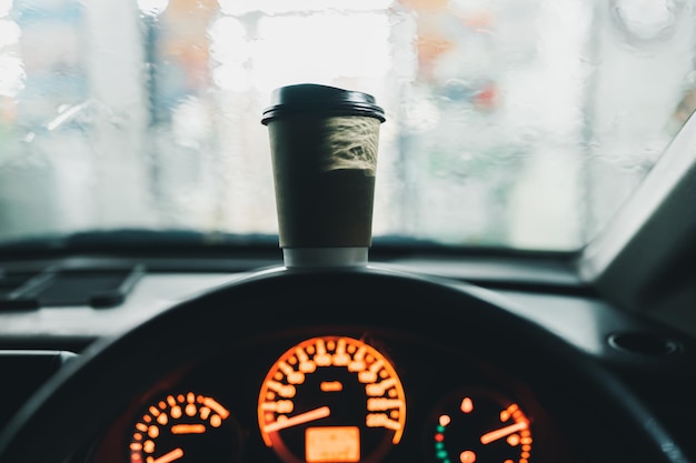 Kaffeetasse auf der Autokonsole während des regnerischen Morgens