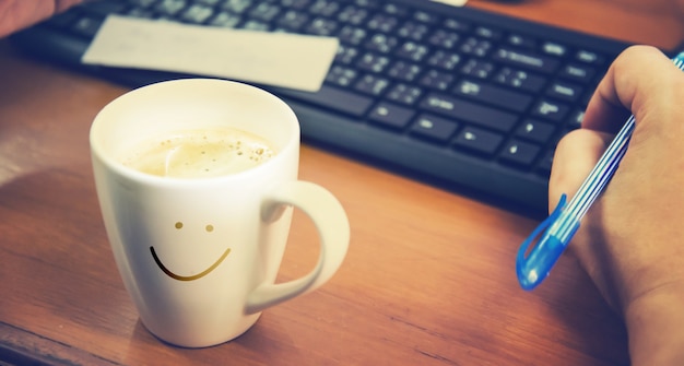 Kaffeetasse auf einem Holztisch mit der Hand