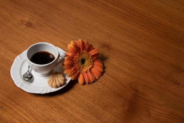 Kaffeetasse auf Holztisch mit Blume daneben