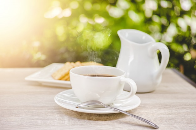 Kaffeetasse auf Holztischmorgenkaffee im Garten - Weinleseton