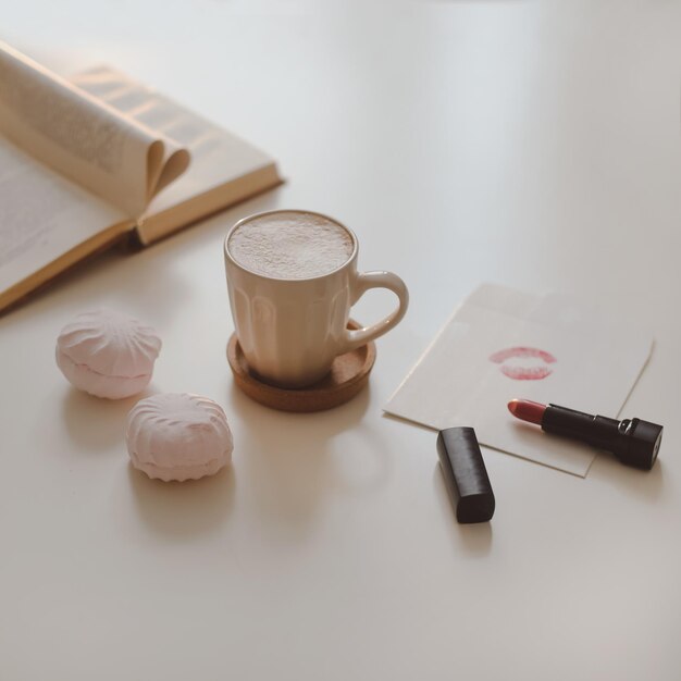 Kaffeetasse-Blumenkerze und ein Buch auf einer Draufsicht des weißen Tabellenhintergrundes