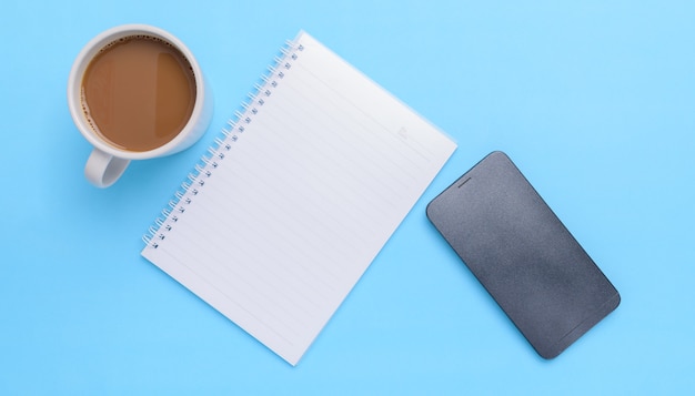 Kaffeetasse, Buch, Smartphone auf blauem Hintergrund