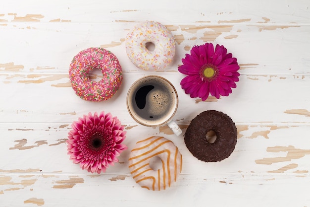 Kaffeetasse-Donuts und Gerbera-Blumen