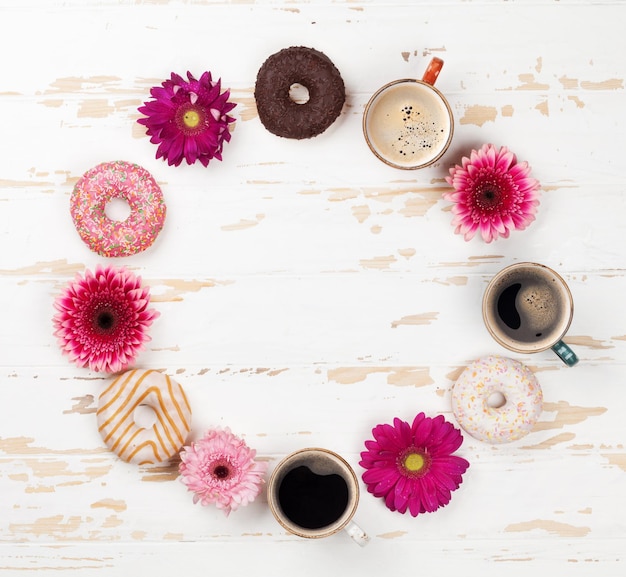 Kaffeetasse-Donuts und Gerbera-Blumen