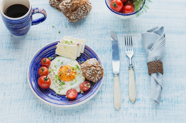 Kaffeetasse, ein Ei, Käse und Kirschtomaten für ein gesundes Frühstück.