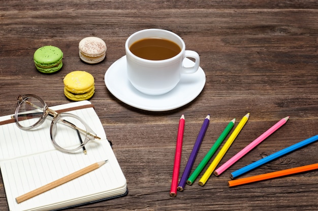 Foto kaffeetasse, makronen, buntstifte und ein notizbuch