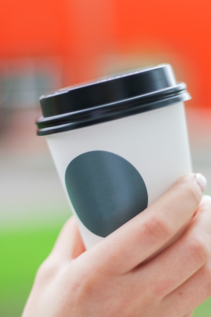 Kaffeetasse mit Aufkleber für Logo in Womans Hand mit flachem DOF