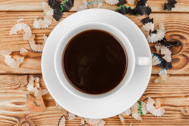 Kaffeetasse mit Bleistiften und Bleistift schneidet auf hölzernen Hintergrund