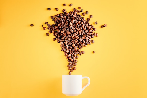 Kaffeetasse mit Bohnen auf gelbem Hintergrund