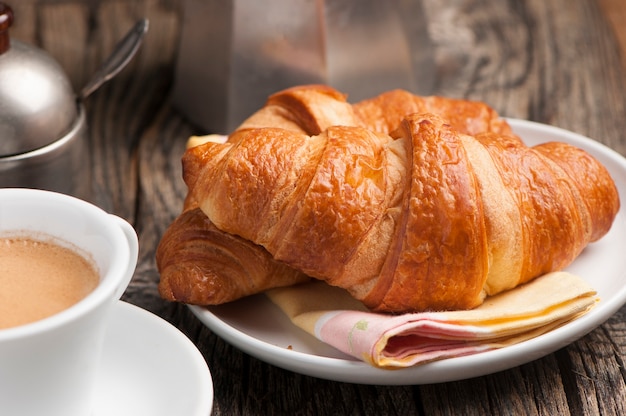 Kaffeetasse mit Croissantfrühstück auf Holztisch