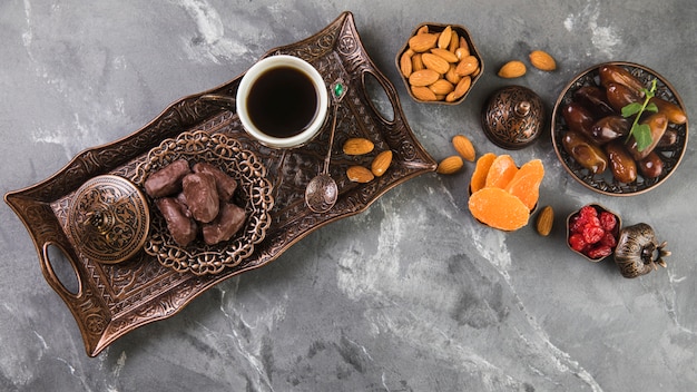 Foto kaffeetasse mit dattelfrucht und mandeln auf tablett