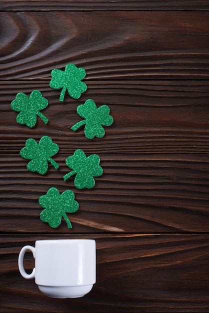 Kaffeetasse mit dreiblättrigen, handgefertigten Shamrock-Blättern auf Holzhintergrund