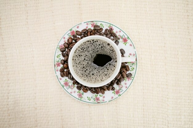 Kaffeetasse mit Käsebrot und Kaffeebohnen an der Seite