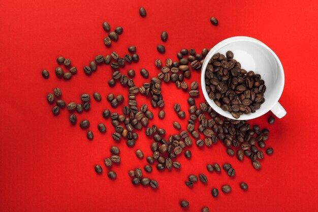 Kaffeetasse mit Kaffeebohnen auf Rot.