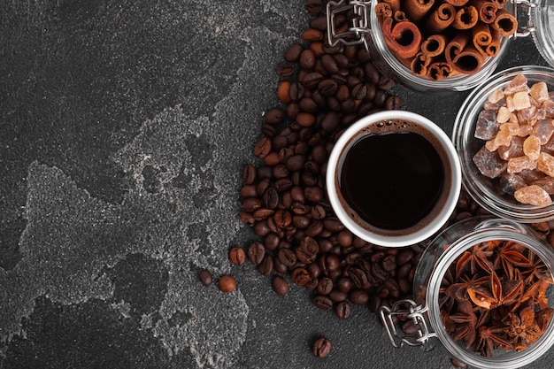 Kaffeetasse mit Kaffeebohnen auf schwarzer Oberfläche Draufsicht