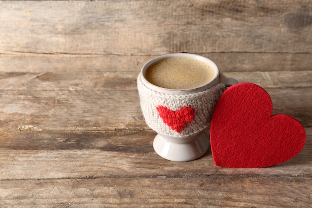 Kaffeetasse mit Milch und Herz auf hölzerner Tischnahaufnahme