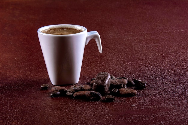 Kaffeetasse mit Pralinen fotografiert auf braun bemaltem Hintergrund