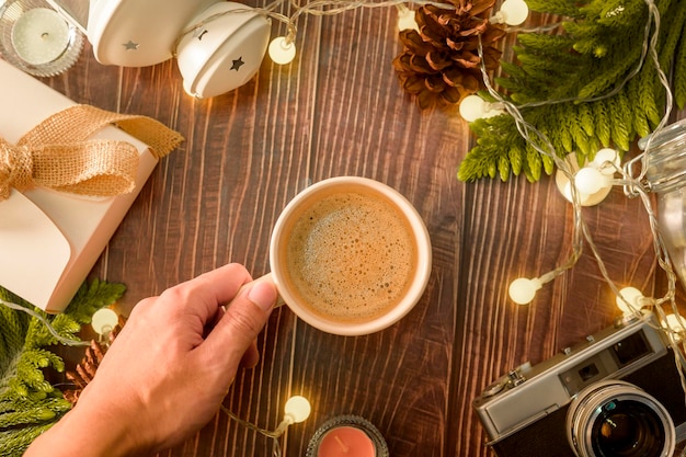 Kaffeetasse über Weihnachtsbeleuchtung Bokeh zu Hause auf Holztischdekorationen Winterurlaub