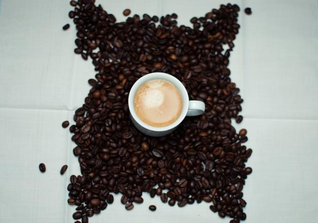 Kaffeetasse umgeben von Kaffeebohnen