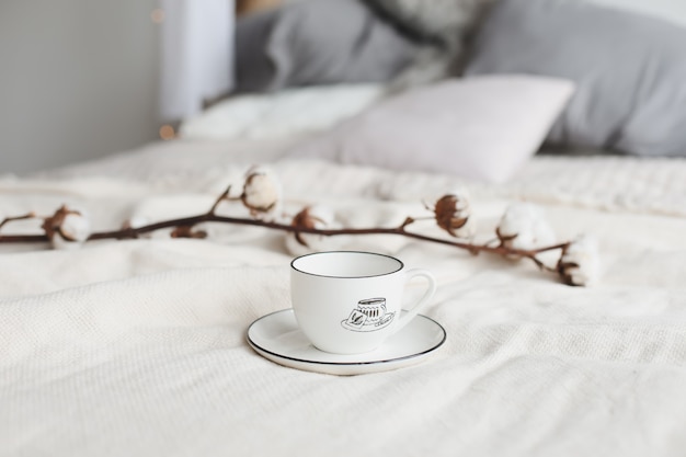 Kaffeetasse und Baumwollblume. Frühstück im Bett.