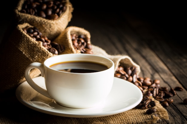 Kaffeetasse und Bohnen auf einem rustikalen Hintergrund.