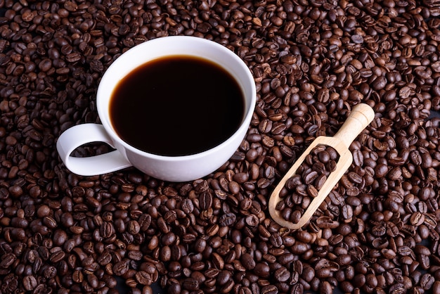 Kaffeetasse und Bohnen mit hölzernem Löffel auf Holztisch