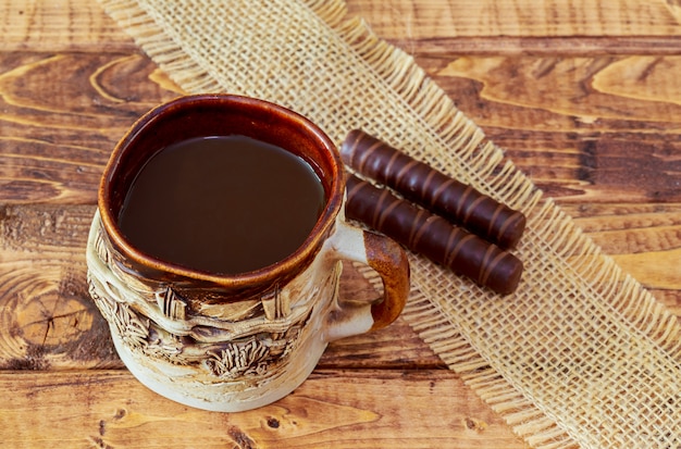 Kaffeetasse und Bohnen, Zimtstangen, Schokolade auf Holztischhintergrund