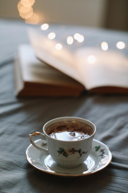 Kaffeetasse und ein Buch im Bett Gemütlicher sonniger Morgen zu Hause Lesen und Frühstücken im Bett Frühlingsstillleben